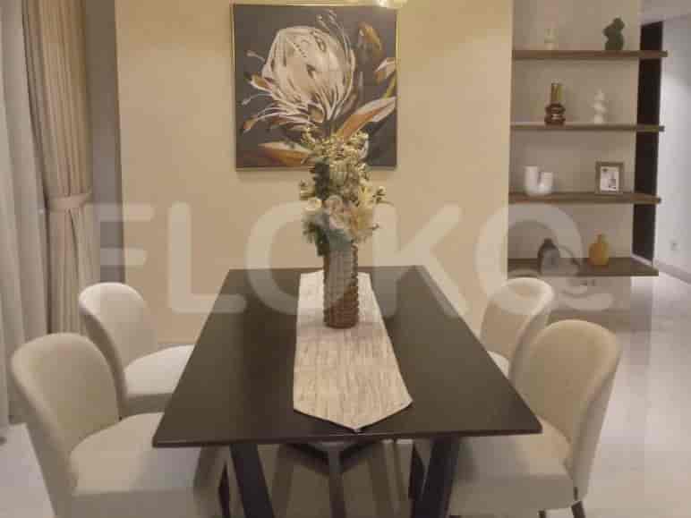 A dining table with six chairs, a centerpiece, and artwork on the wall.