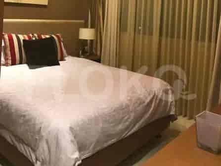 A cozy bedroom featuring a bed with decorative pillows, a wooden side table, and a lamp.