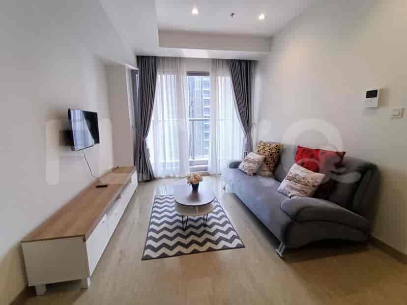 A modern living room with a grey sofa, TV, and large windows.