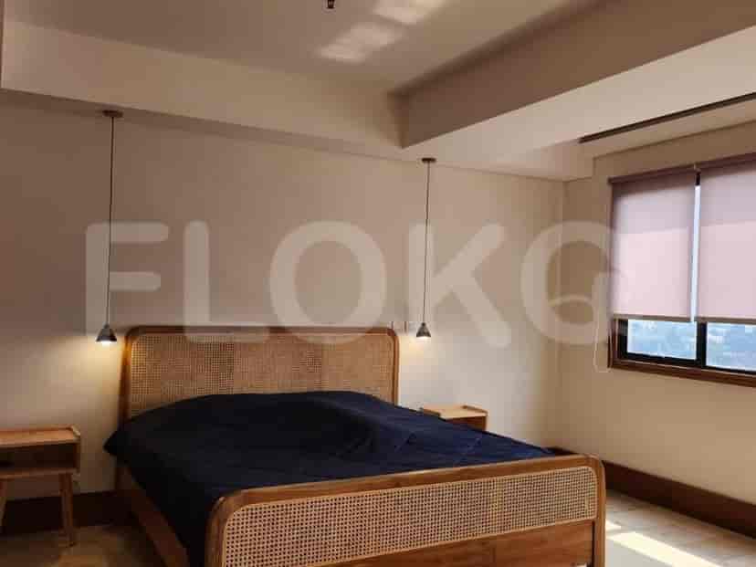 A bedroom with a queen-sized bed with a rattan headboard, bedside tables, and pendant lights.