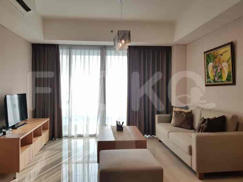 A modern living room with a sofa, coffee table, TV console, and large windows.