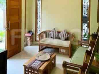 A living room furnished in traditional Javanese style with a wooden sofa, coffee table, and decorative elements.