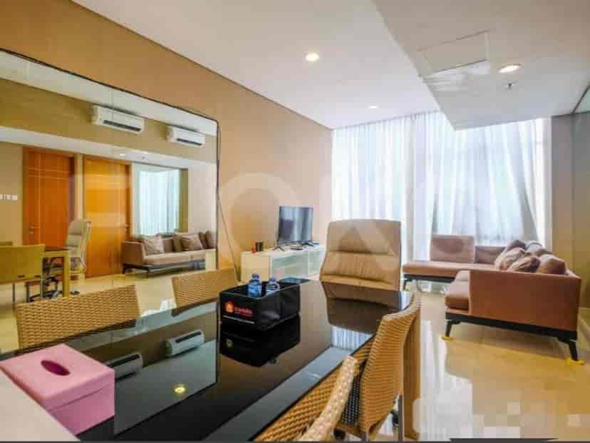 A dining area with a black dining table and wicker chairs, connected to a living space with a sofa and entertainment center.