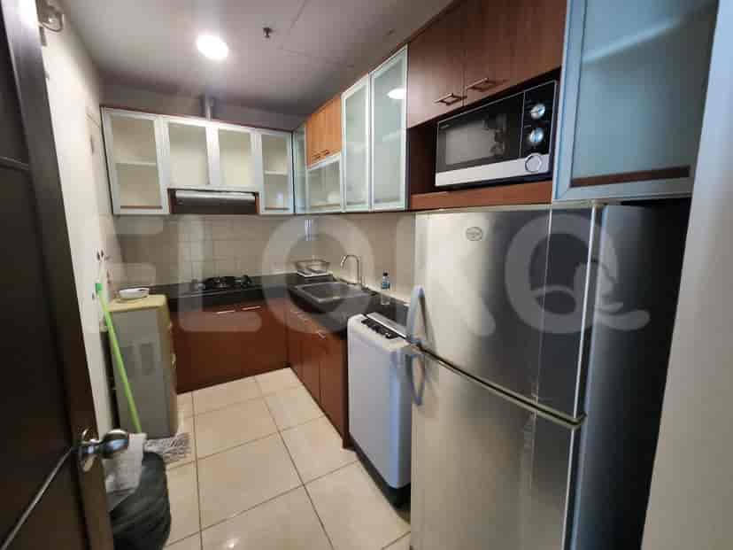 A compact kitchen with wooden cabinets, a refrigerator, a microwave, and a stove.