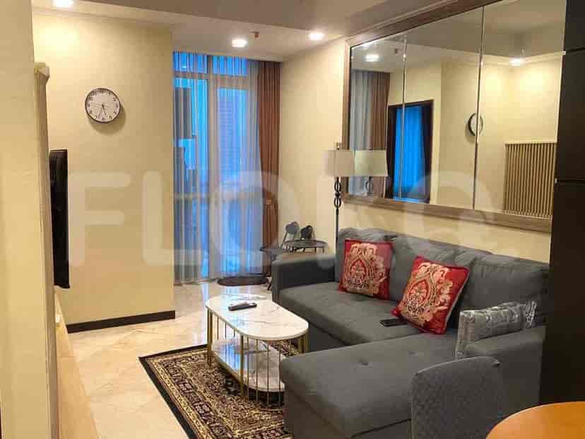 Ruang tamu modern yang menampilkan sofa sectional abu-abu, meja kopi marmer, dan cermin besar yang memantulkan ruangan.