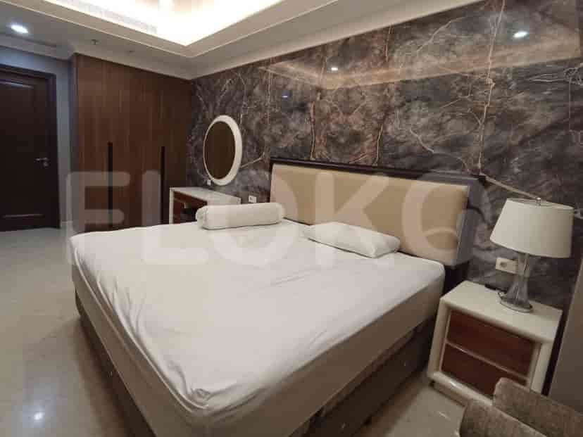 A bedroom with a large bed, a marble accent wall, and a vanity area.