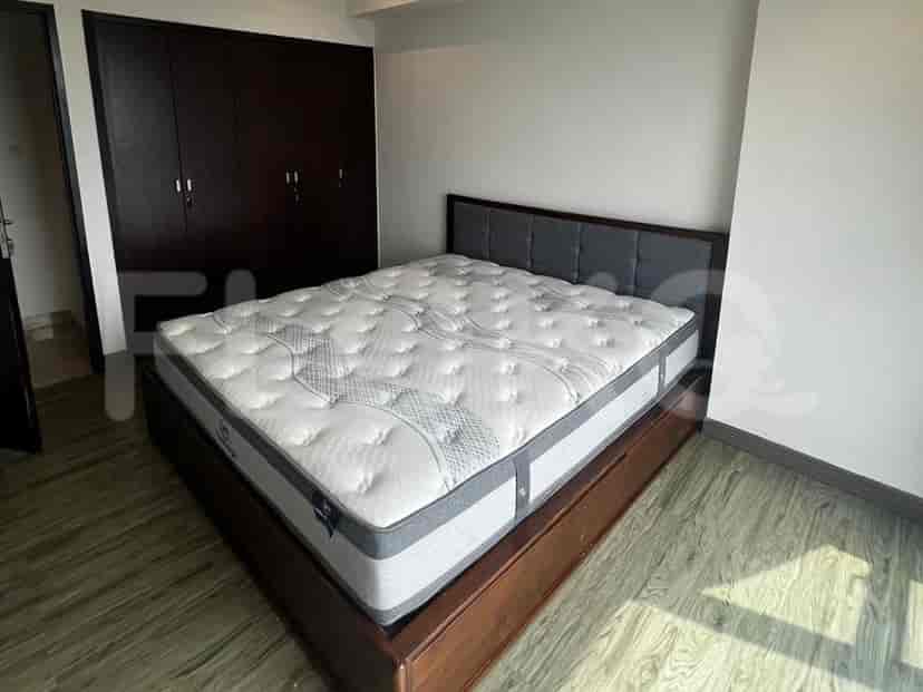 Sebuah kamar tidur dengan tempat tidur besar, lemari kayu gelap, dan lantai kayu terang.