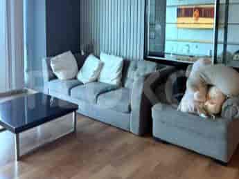 Sofa modular abu-abu dengan bantal putih tertata di sekeliling meja kopi hitam.