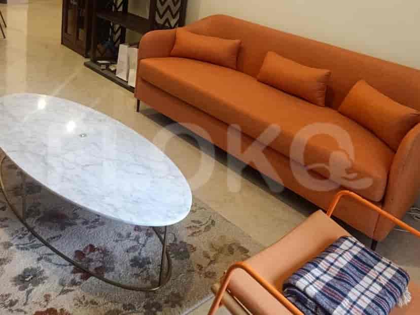 A living room with an orange sofa, marble coffee table, and patterned rug.