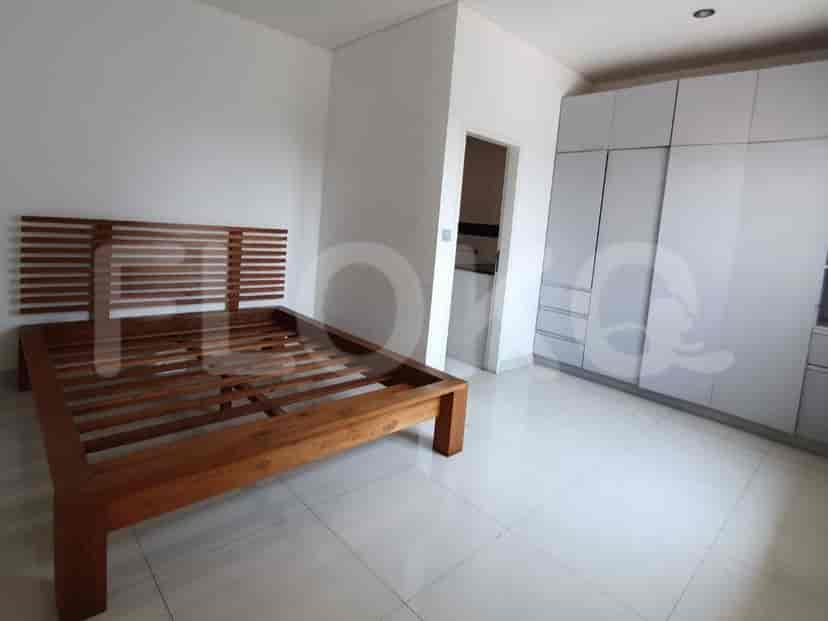 Kamar tidur dengan rangka tempat tidur kayu, lemari pakaian putih besar, dan pintu menuju kamar mandi dalam.