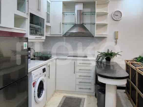 Dapur modern dengan kabinet putih, tudung asap baja tahan karat, dan meja dapur dengan area makan terpasang.