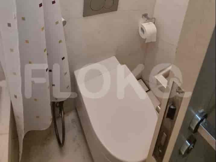 Kamar mandi bersih dan modern menampilkan toilet dan pancuran dengan tirai berpola.