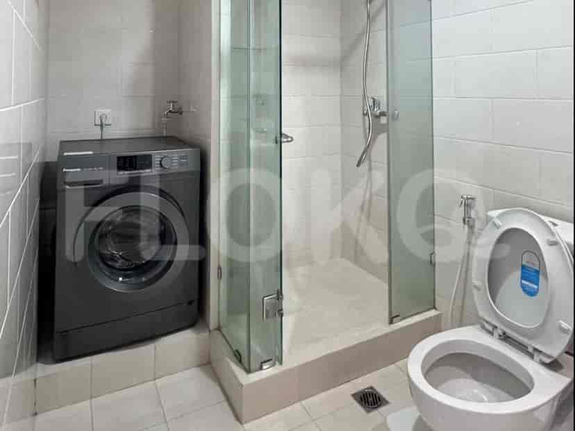 A bathroom with a washing machine, glass shower, and toilet.