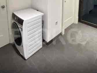 A laundry area with a modern washing machine and tiled flooring.