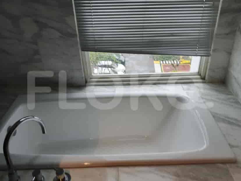 A bathroom with a bathtub, window, and marble walls.