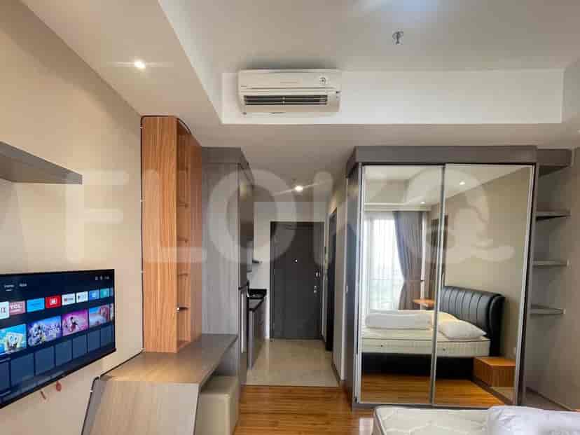 A compact studio apartment with a bed, TV, kitchenette, and wardrobe.