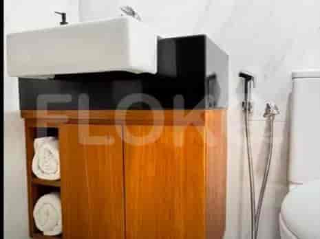 Kamar mandi yang ringkas dengan wastafel, lemari kayu, dan toilet.