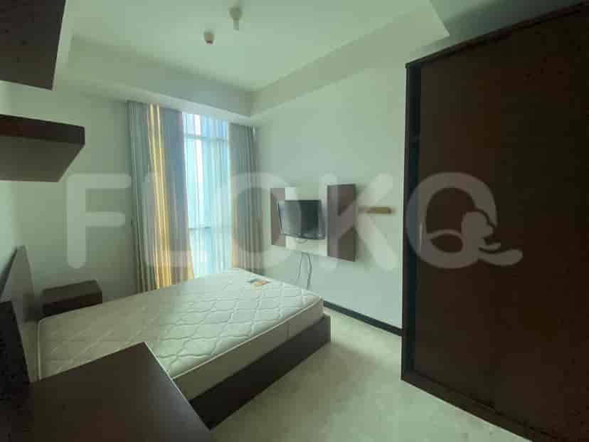 A bedroom with a queen-size bed, wall-mounted TV, and a large window.
