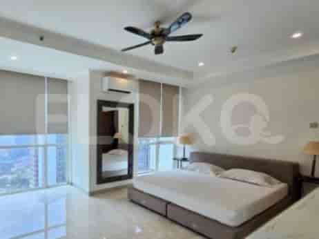 A bedroom with a king-size bed, bedside tables, and large windows.