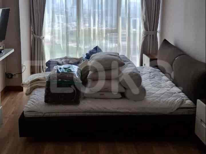 A bedroom with a large bed covered in pillows and blankets, and a window with curtains.