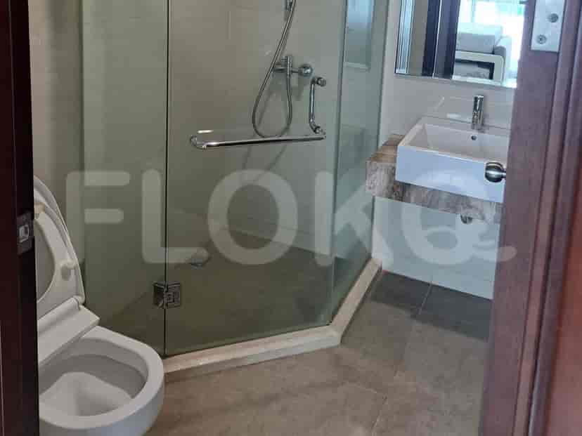 A modern bathroom with a glass-enclosed shower, a white toilet, and a sink with a marble countertop.