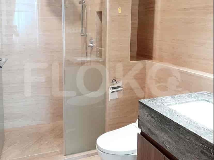 A modern bathroom with a walk-in shower, toilet, and a stone-top vanity.