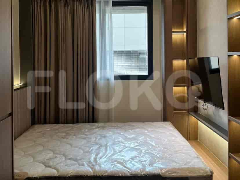 Kamar tidur dengan kasur tertutup, lemari kayu, dan jendela.