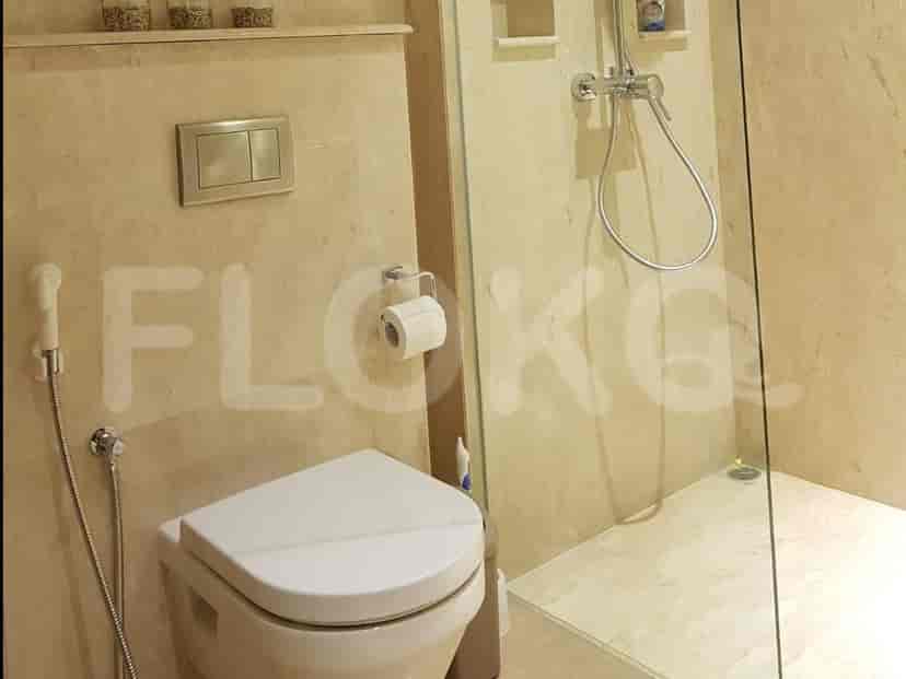 Modern bathroom with a white toilet, glass shower, and marble finishes.