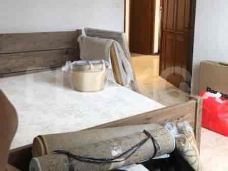 Bedroom with bed and rolled rugs.