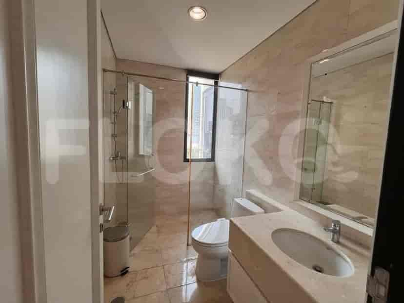 A modern bathroom with marble-tiled walls and floor, a glass-enclosed shower, and a vanity.