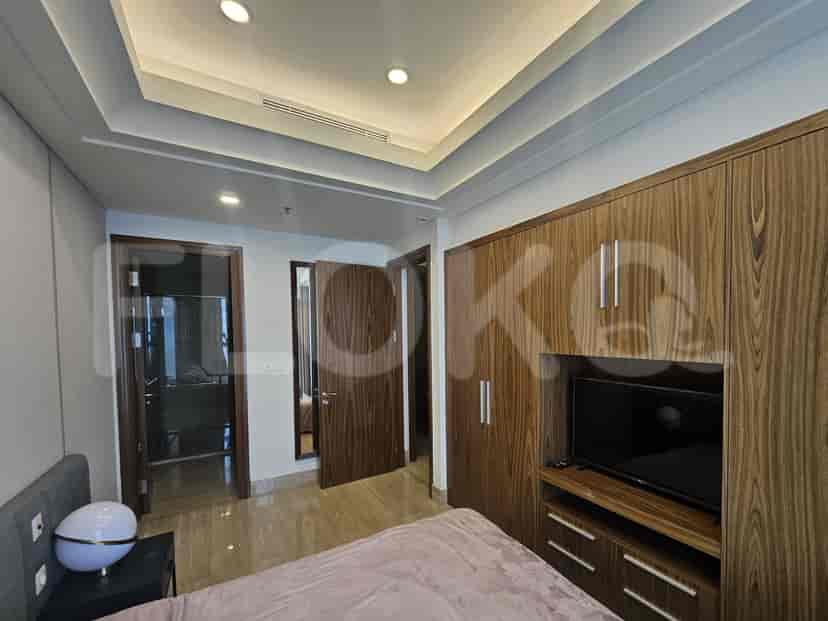 Modern bedroom with wooden paneling, TV, and a warm color palette.