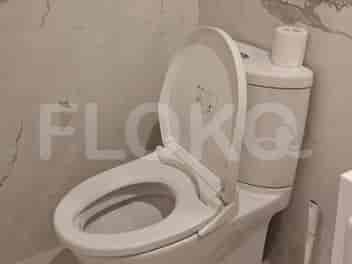 A toilet with an open lid and a roll of toilet paper on the tank.