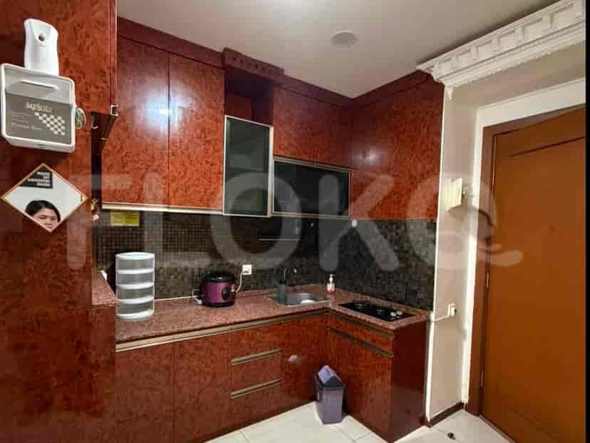 Sebuah dapur ringkas dengan lemari merah kecoklatan, meja granit, dan kompor.