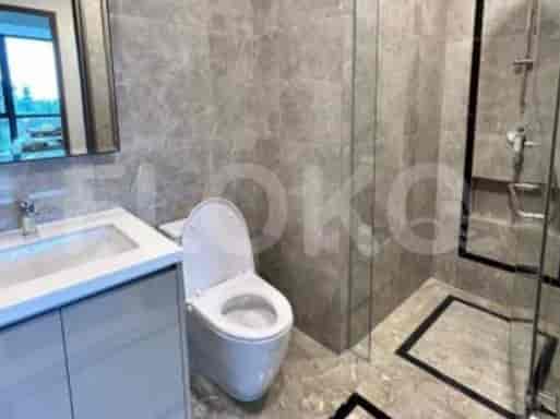 Kamar mandi modern dengan toilet, meja rias dengan wastafel, dan pancuran berdinding kaca.