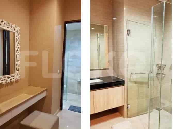 Area wastafel dengan cermin dan pintu menuju kamar mandi dengan pancuran kaca.