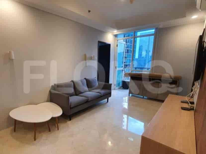 Tampilan ruang tamu yang menunjukkan sofa abu-abu, meja kopi, dan jendela besar dengan pemandangan kota.