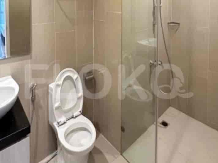 A modern bathroom with a toilet, a sink, and a glass-enclosed shower area with tiled walls.