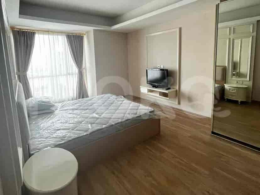 Kamar tidur terang dengan tempat tidur berlaken putih bersih, TV terpasang di dinding, dan lemari pakaian besar bercermin.
