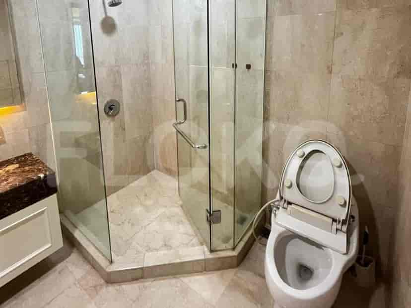 Kamar mandi modern dengan shower berkaca, toilet, dan ubin marmer elegan.