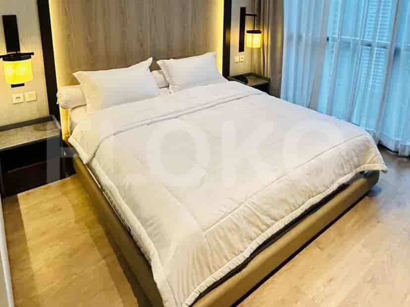 A bedroom with a large bed, white bedding, wooden headboard with integrated lighting, and bedside tables.