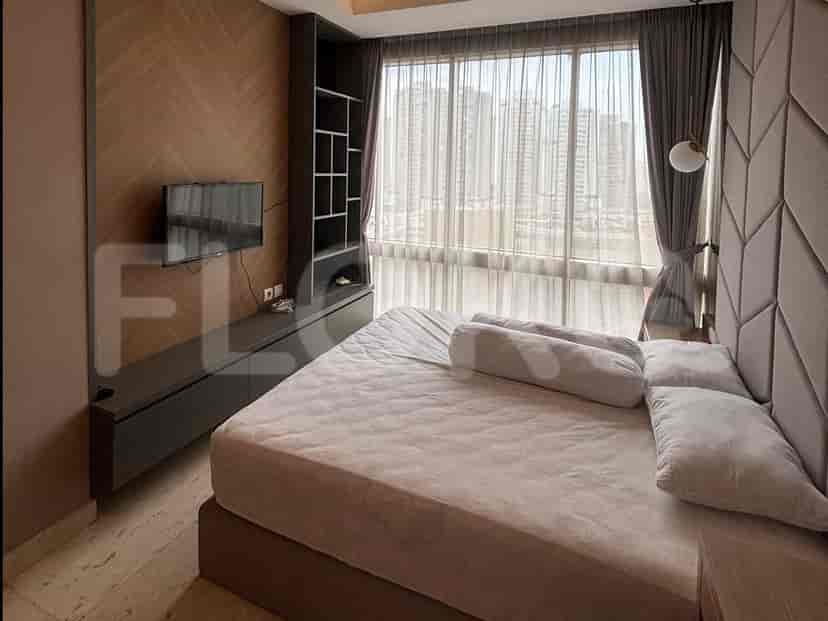 A bedroom with a large bed, a wall-mounted TV, and floor-to-ceiling windows offering a city view.