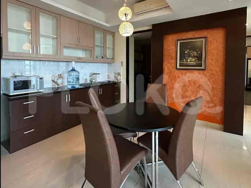 A modern kitchen and dining area with light wood cabinets, dark countertops, a round dining table with four chairs, and a bar with stools.