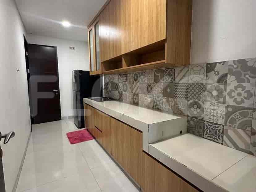 Modern kitchen with wooden cabinets, tiled backsplash, and a black refrigerator.