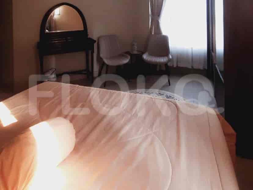 Bedroom featuring a bed with a peach-colored blanket, chairs, and a mirror.