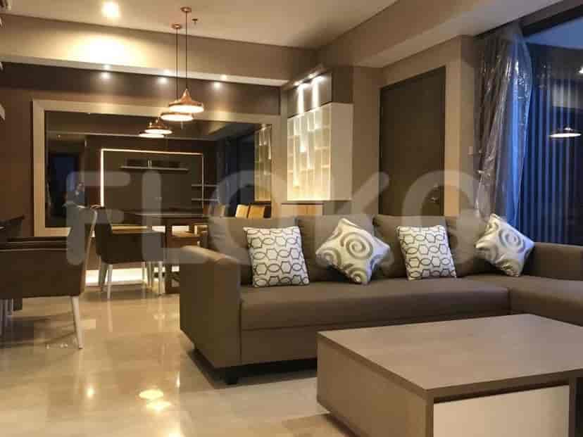 A spacious living room with a sectional sofa, coffee table, and dining area visible in the background through a large mirror.