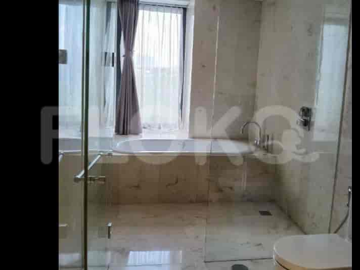 Kamar mandi mewah dengan ubin marmer, bak mandi berdiri sendiri, dan pancuran tertutup kaca.