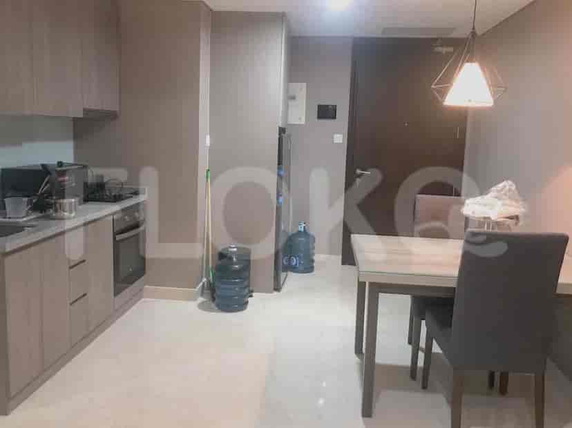 A compact kitchen with wooden cabinets and appliances, adjacent to a small dining area with two chairs.