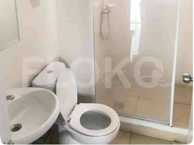 Kamar mandi ringkas dengan toilet, wastafel, dan bilik shower.