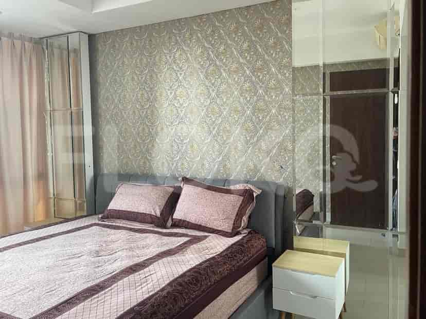 A bedroom with a king-sized bed, patterned wallpaper, mirrored wardrobes, and sheer curtains.