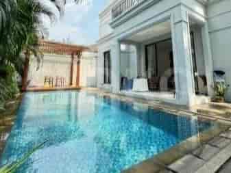 A private swimming pool with blue water surrounded by a paved deck and lounge chairs, adjacent to a covered patio area.